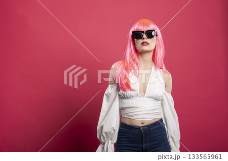Beautiful cheerful woman wearing black shades and white outfit, laughing and posing confidently against a pink studio background. Vibrant female expresses joy and modern fashion vibes. Beautiful cheerful woman wearing black shades and white outfit, laughing and posing confidently against a pink studio background. Vibrant female expresses joy and modern fashion vibes. 133565961
