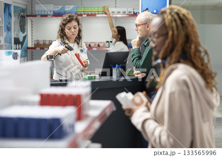 Woman employee offering prescription drugs to old person at checkout, friendly assistance and guidance in a modern drugstore. The right treatment and proper use of medicaments. Woman employee offering prescription drugs to old person at checkout, friendly assistance and guidance in a modern drugstore. The right treatment and proper use of medicaments. 133565996