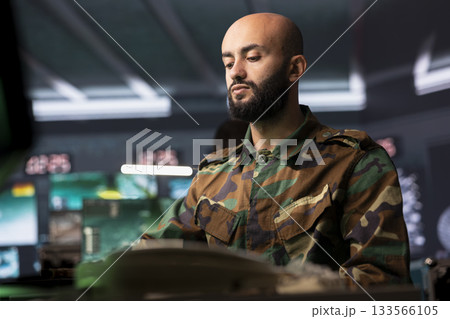 Counterintelligence specialist in control center combating terrorism using detection system. Middle Eastern intelligence officer protecting national borders by tracking terrorists entering country Counterintelligence specialist in control center combating terrorism using detection system. Middle Eastern intelligence officer protecting national borders by tracking terrorists entering country 133566105