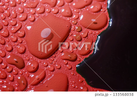 Closeup view of white and black fluid drops on a textured red background Closeup view of white and black fluid drops on a textured red background 133568038