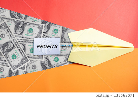 Yellow paper plane with text of profit and dollar bills. Concept of business profit, financial growth, investment, and success Yellow paper plane with text of profit and dollar bills. Concept of business profit, financial growth, investment, and success 133568071