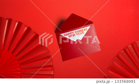 Red envelope and red folding fan with Chinese New Year message on a red background. Happy Lunar or Chinese New Year celebration 133568091