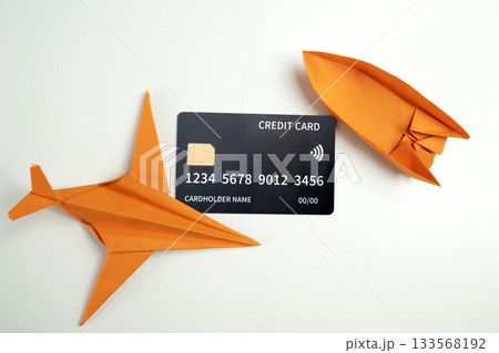 Credit card with an orange paper airplane and boat on a white background. Concept of finance and travel Credit card with an orange paper airplane and boat on a white background. Concept of finance and travel 133568192