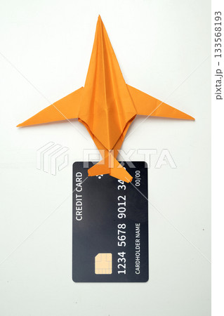 Credit card and orange paper airplane on a white background. Concept of finance and travel Credit card and orange paper airplane on a white background. Concept of finance and travel 133568193