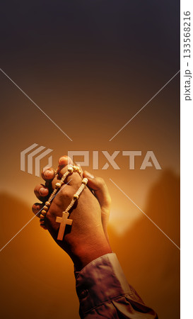 Prayer holding rosary beads with dark dramatic sky background. Concept of Christianity, religious, faith, Jesus, or belief 133568216