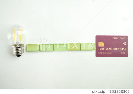 Top view of a lightbulb with rectangular blocks and a debit or credit card on a white background. Mockup or template. Flat lay. Concept of Security, finance, and business Top view of a lightbulb with rectangular blocks and a debit or credit card on a white background. Mockup or template. Flat lay. Concept of Security, finance, and business 133568305