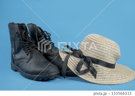 Black shoes and a straw hat with a black ribbon on a blue background. Concept of travel, summer, or vacation 133568315