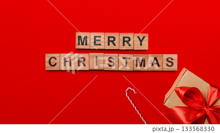 Greeting of Merry Christmas text with a gift box and a candy cane on a red background. Holiday greetings or winter themes. Concept of the Merry Christmas celebration Greeting of Merry Christmas text with a gift box and a candy cane on a red background. Holiday greetings or winter themes. Concept of the Merry Christmas celebration 133568330