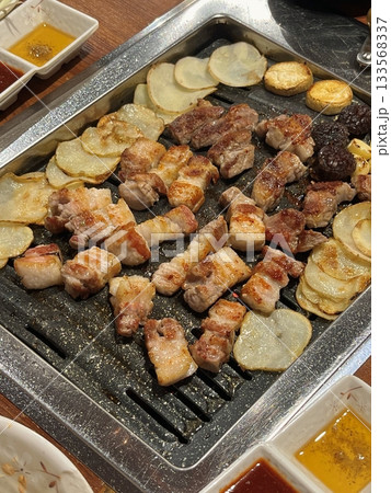 Grilled samgyeopsal, showcasing thick slices of pork belly sizzling on the grill. A popular Korean barbecue dish, capturing the essence of a delicious dining experience. Grilled samgyeopsal, showcasing thick slices of pork belly sizzling on the grill. A popular Korean barbecue dish, capturing the essence of a delicious dining experience. 133568337
