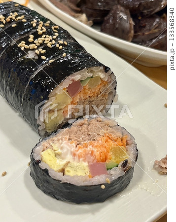 Delicious kimbap rolls filled with fresh vegetables, seasoned rice, and savory proteins, all wrapped in crisp seaweed. A perfect combination of flavor and texture in every bite. 133568340