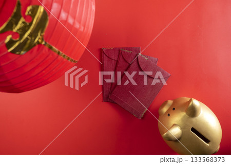 Red Chinese lantern with red envelopes or angpao and a piggy bank on a red background. Mockup, template, or copy space. Decoration for the Lunar or Chinese New Year celebration 133568373