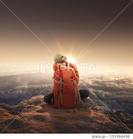 Indonesian southeast asian muslim woman with a backpack sitting with the cloudscape landscape view. Concept of travel 133568436