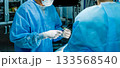 A surgeon wearing sterile gloves holds a large syringe containing medication. 133568540