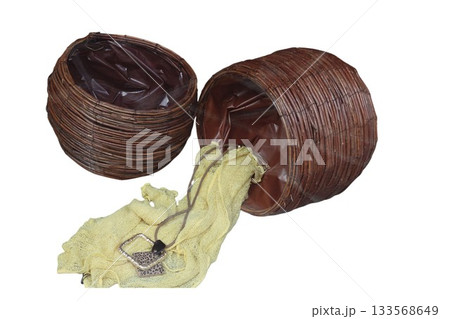 Wicker basket spilling a yellow cloth and necklace 133568649