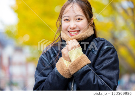 コートを着た笑顔の若い女性 133569986