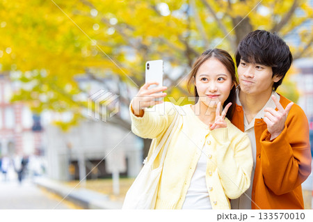 銀杏の前で自撮りをするカップル 133570010