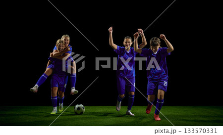 Teenage soccer players celebrating win with mixed running and lifting gestures 133570331