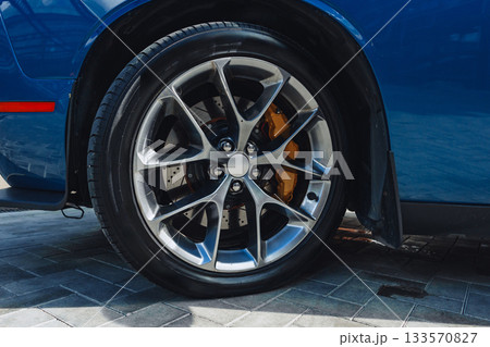 Sleek blue sports car wheel with shiny alloy rims and detailed brake calipers 133570827