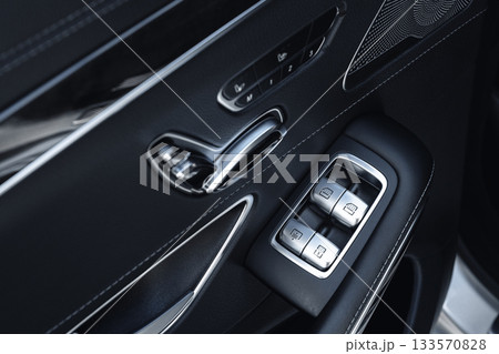 Detail of car door controls showing window switches and interior design features 133570828
