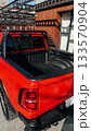 Bright red pickup truck parked in modern outdoor setting during sunny daytime 133570904