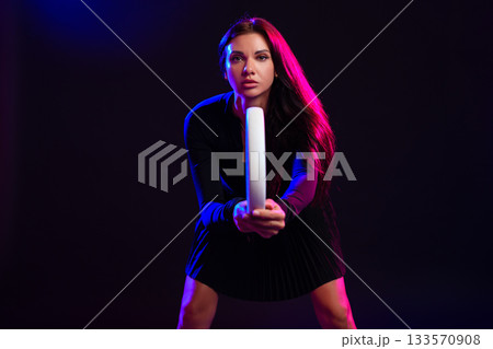 Woman posing with a lighting rod in a colorful studio environment for a creative photo shoot 133570908