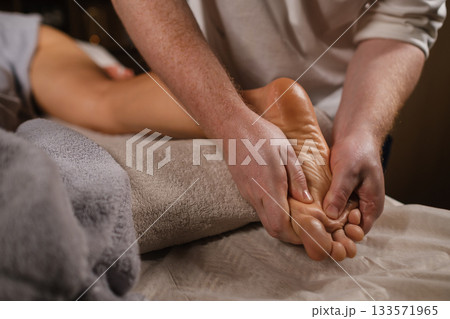 Relaxing foot massage at a wellness center during a soothing evening session Relaxing foot massage at a wellness center during a soothing evening session 133571965