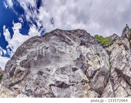 Panorama of stabilized rock wall with protective mesh netting Panorama of stabilized rock wall with protective mesh netting 133572064