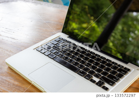 Outdoor Laptop On Wooden Table With Greenery Reflection For Modern Tech And Work In Bright Day 133572297
