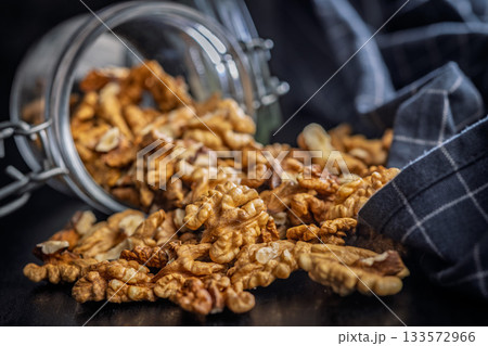Peeled walnut kernels in jar on black table. 133572966