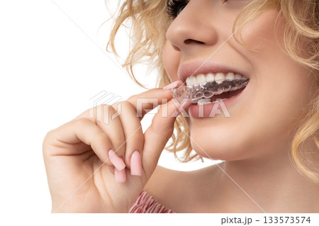 Woman preps with clear aligner by her smile, isolated, PNG Woman preps with clear aligner by her smile, isolated, PNG 133573574