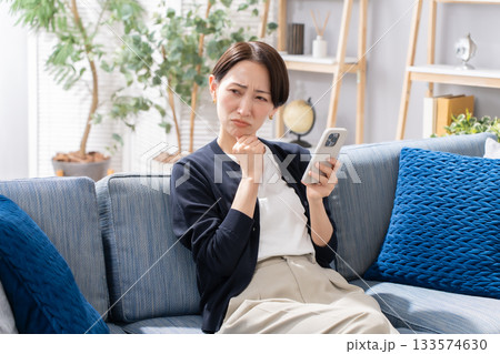 ソファーでスマホを操作する女性 悩む ソファーでスマホを操作する女性 悩む 133574630