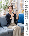 ソファーでスマホを指さす女性 133574640