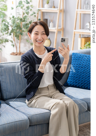 ソファーでスマホを指さす女性 133574640