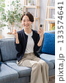 ソファーでスマホを操作する女性　ガッツポーズ 133574641