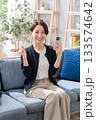 ソファーでスマホを操作する女性　ガッツポーズ 133574642