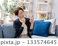 ソファーでスマホを操作する女性　悩む 133574645