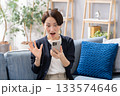 ソファーでスマホを操作する女性　驚く 133574646