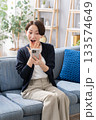 ソファーでスマホを操作する女性　驚く 133574649