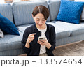 ソファーでスマホを操作する女性 133574654