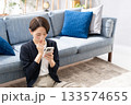 ソファーでスマホを操作する女性　悩む 133574655