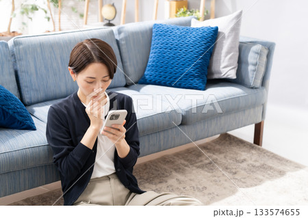 ソファーでスマホを操作する女性　悩む 133574655