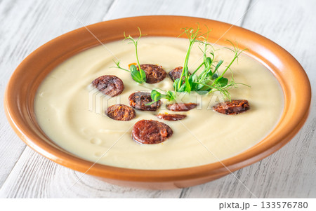 Creamy cauliflower soup with spicy chorizo served warmly in terracotta bowl on white table Creamy cauliflower soup with spicy chorizo served warmly in terracotta bowl on white table 133576780