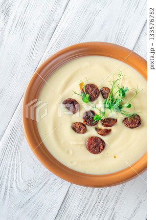 Creamy cauliflower soup with spicy chorizo served warmly in terracotta bowl on white table Creamy cauliflower soup with spicy chorizo served warmly in terracotta bowl on white table 133576782