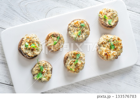 Melted blue cheese fills baked mushroom caps creating savory aroma on simple white plate Melted blue cheese fills baked mushroom caps creating savory aroma on simple white plate 133576783