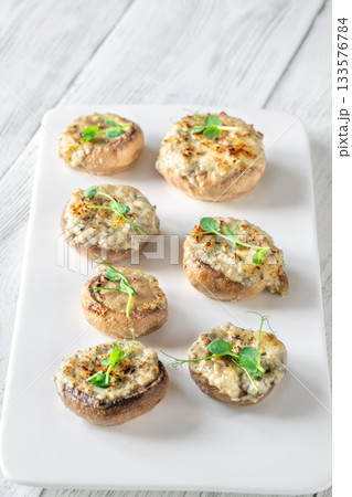 Melted blue cheese fills baked mushroom caps creating savory aroma on simple white plate Melted blue cheese fills baked mushroom caps creating savory aroma on simple white plate 133576784