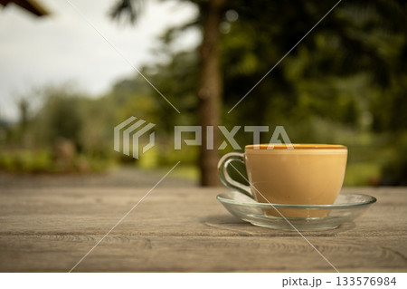 Coffee on a table with greenery behind it 133576984