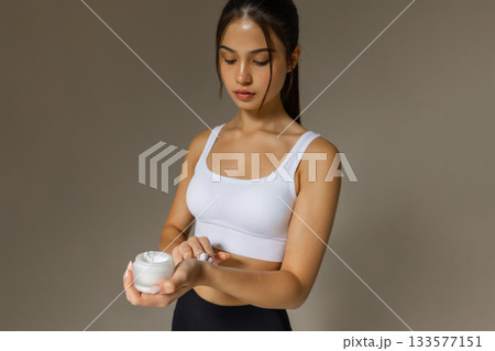 Young brunette woman applying moisturizing cream on hand, skincare routine, beauty care, soft skin, cosmetic product usage for daily skincare and healthy glowing skin. 133577151