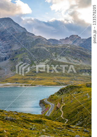 Evening light casts a warm glow over Lago Bianco at Bernina Pass. Surrounded by the majestic Alps, this tranquil alpine lake features glacial waters reflecting the rugged mountain landscape. Evening light casts a warm glow over Lago Bianco at Bernina Pass. Surrounded by the majestic Alps, this tranquil alpine lake features glacial waters reflecting the rugged mountain landscape. 133578205