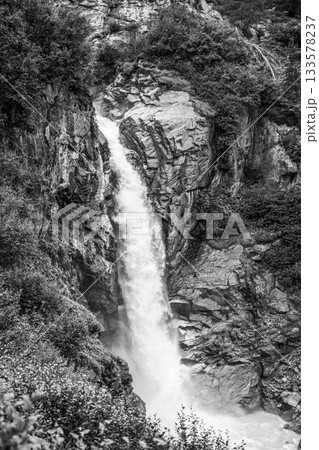 Wild alpine waterfall on Schlatenbach mountain stream. Gschloesstal Valley, Hohe Tauern National Park, East Tyrol, Austrian Alps. Black and white image. 133578237