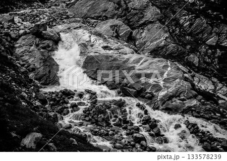 Wild alpine waterfall on Schlatenbach mountain stream. Gschloesstal Valley, Hohe Tauern National Park, East Tyrol, Austrian Alps. Black and white image. Wild alpine waterfall on Schlatenbach mountain stream. Gschloesstal Valley, Hohe Tauern National Park, East Tyrol, Austrian Alps. Black and white image. 133578239